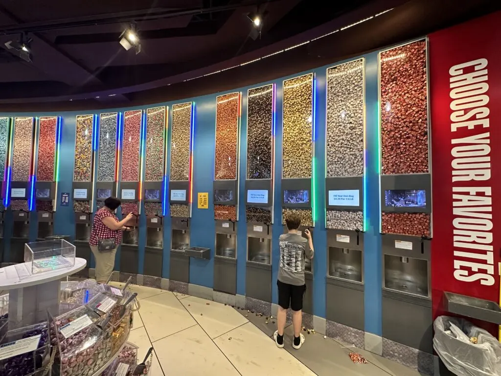 A wall of self service kiss dispensers. Above the dispensers was glass holding back the bulk candy  that extended to the ceiling. 