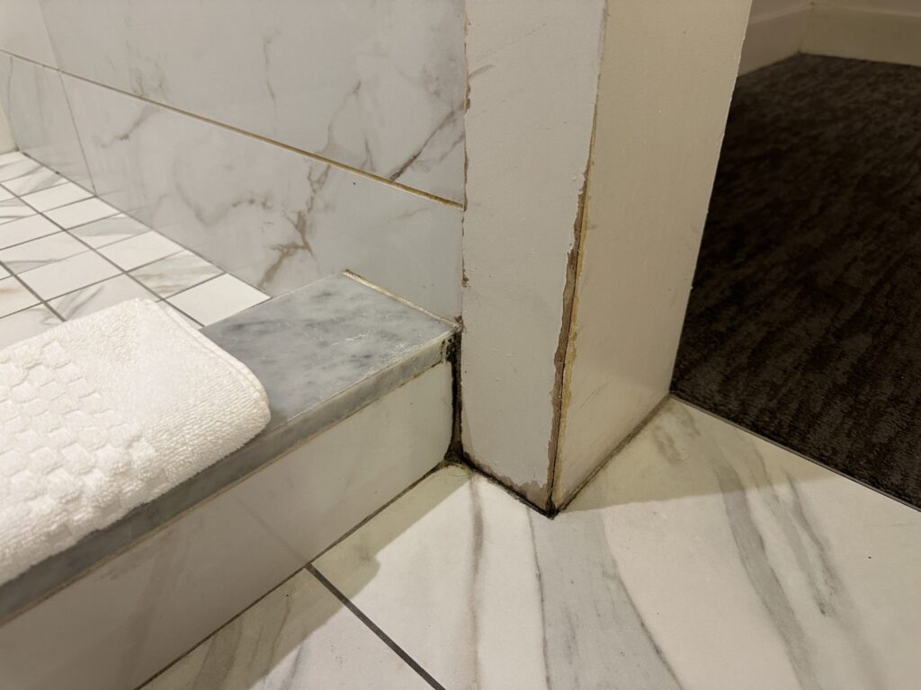 A corner beam in the shower area that appears to be very weathered by water and scuffing.