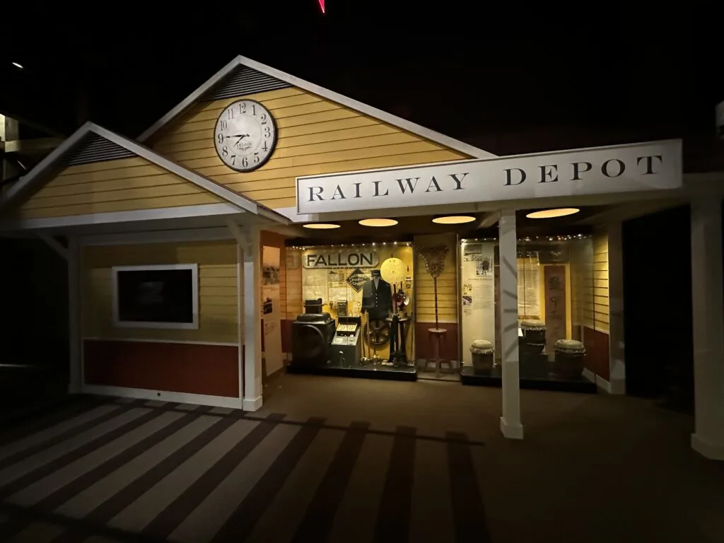 The exterior of a Railway Depot recreation. Out front are a number of artifacts displayed behind glass. 