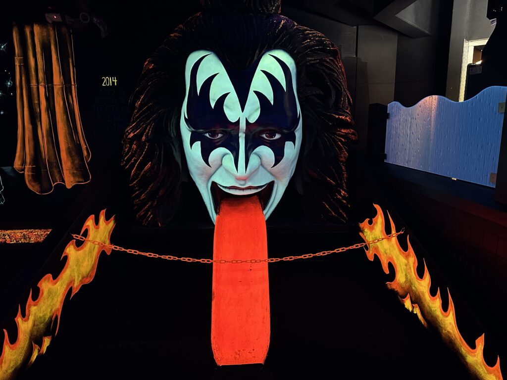 A huge band member face with tounge extended glowing under the black light. The tounge doubles as a ramp to hit your ball up into the mouth. 