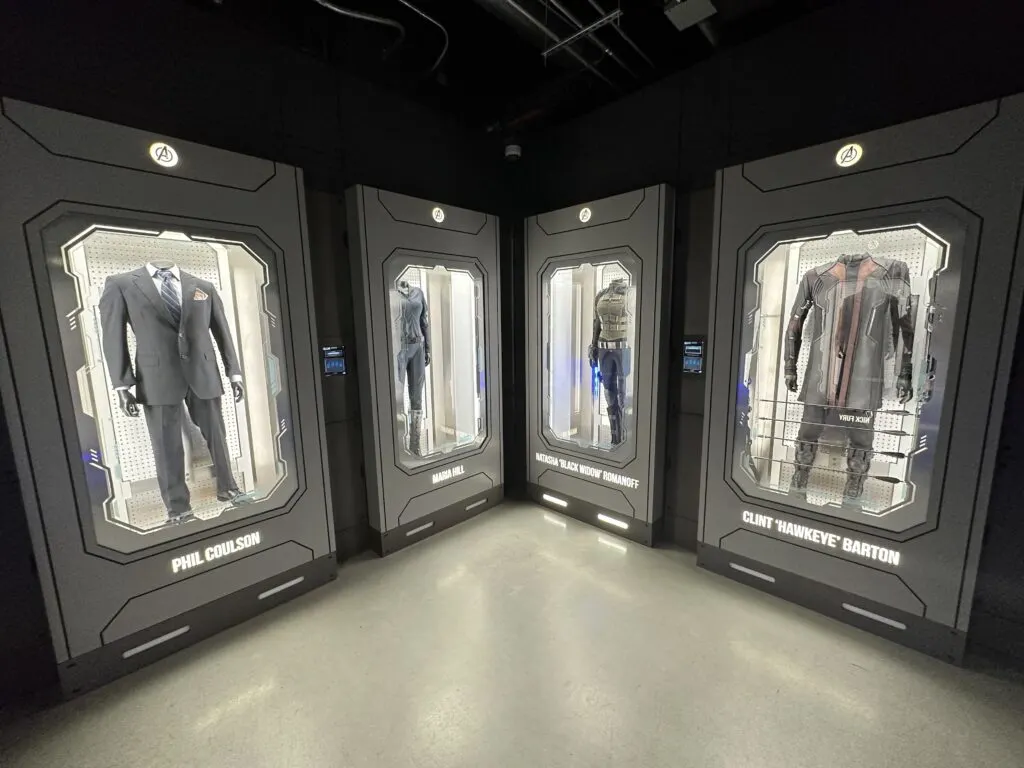 Movie costumes and clothing are behind glass in illuminated lockers.
