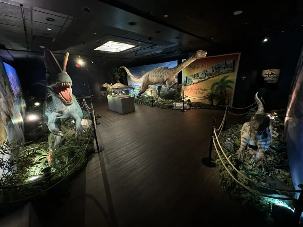 A room full of 3 different dinosaurs shot at a wide angle. 