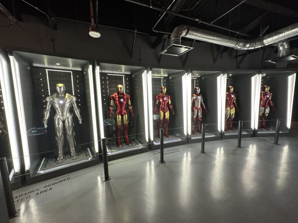 A row of Iron Man suits in illuminated cabinets. 