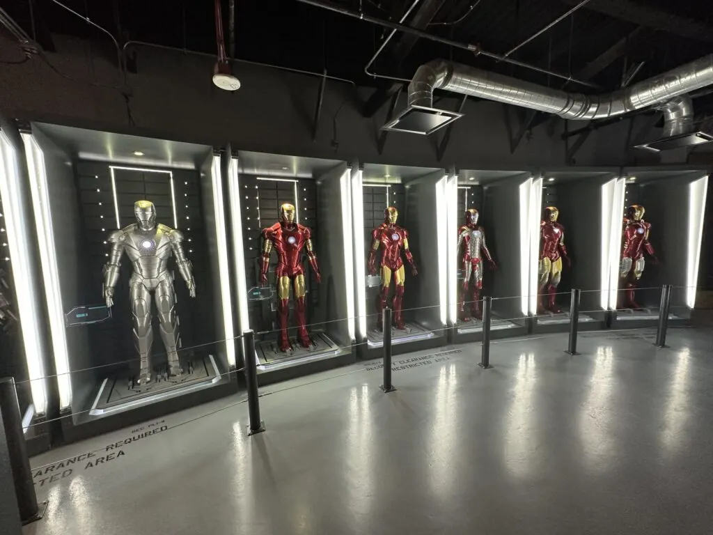 A row of Iron Man suits in illuminated cabinets.