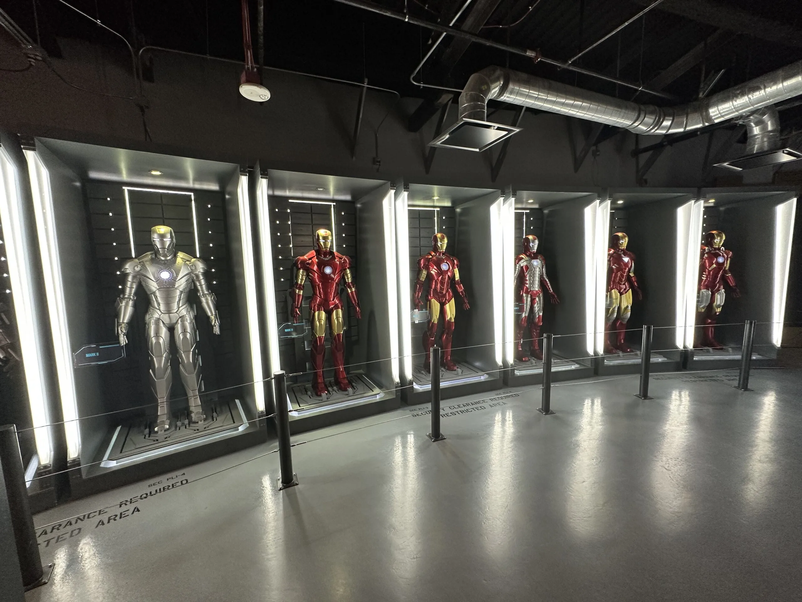 A row of Iron Man suits in illuminated cabinets.