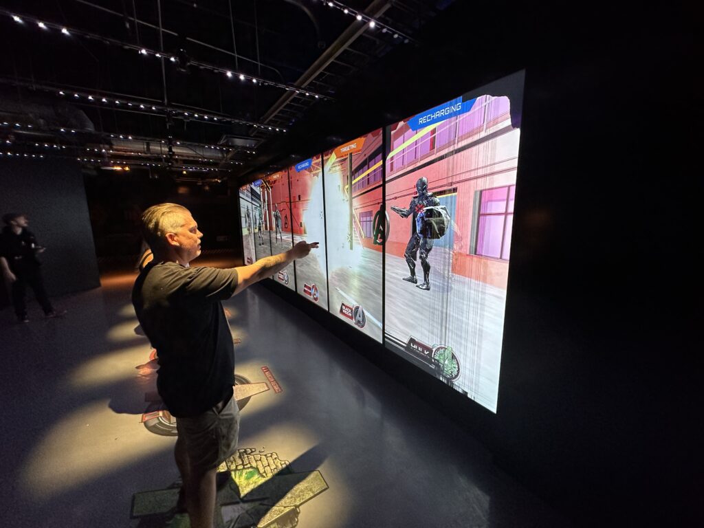 Participants point a controller at a video wall to "shoot" the bad guys.
