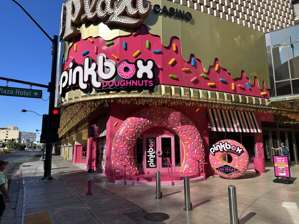 Exterior of Pinkbox Doughnuts at Plaza, which is very pink and features a door that forces you to walk through a pink doughnut. 