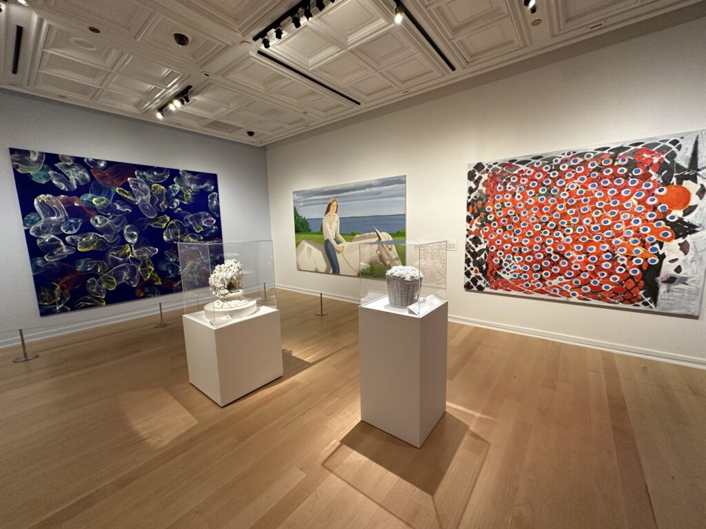 2 white sculptures in glass cases stand in the middle of the room surrounded by more wall art.