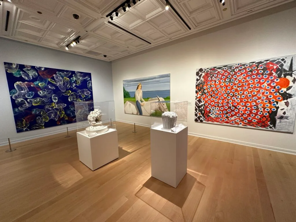 2 white sculptures in glass cases stand in the middle of the room surrounded by more wall art.