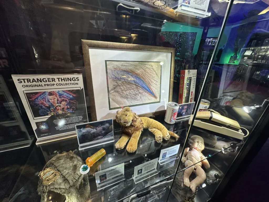 A collection of props from STranger Things that include a drawing by Will and one of Hopper's beer cans. 