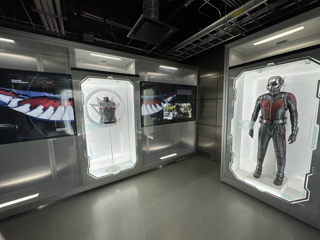 Movie suits and props on display in illuminated glass cases. 