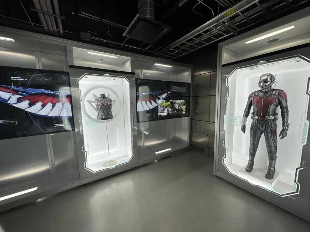 Movie suits and props on display in illuminated glass cases.