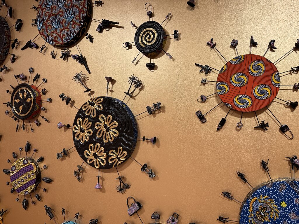 Decorative wall art which includes small model handguns, knives, boots, palm trees, and more. 