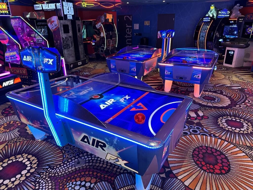 3 blue air hockey tables sit empty, waiting for players. 