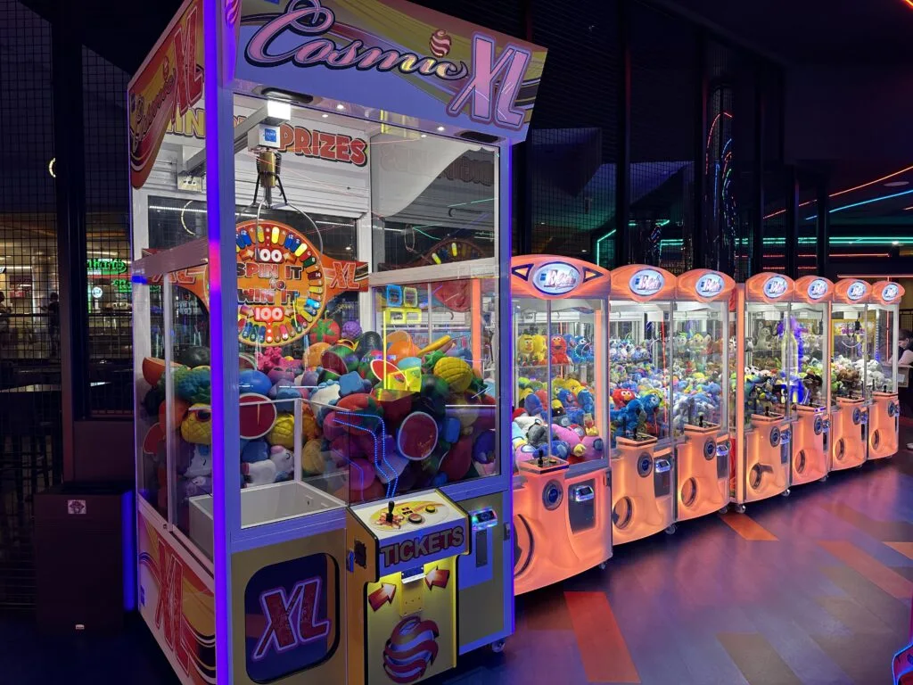 A row of claw games extends into the distance. 