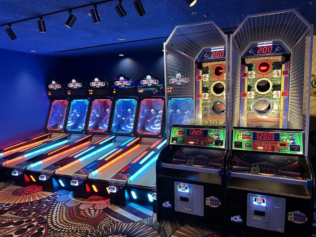 A row of skee ball games sit next to a couple of target throwing arcade games. 