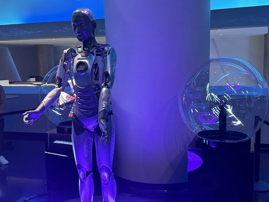 A human-like robot stands on a podium fielding questions from the audience.
