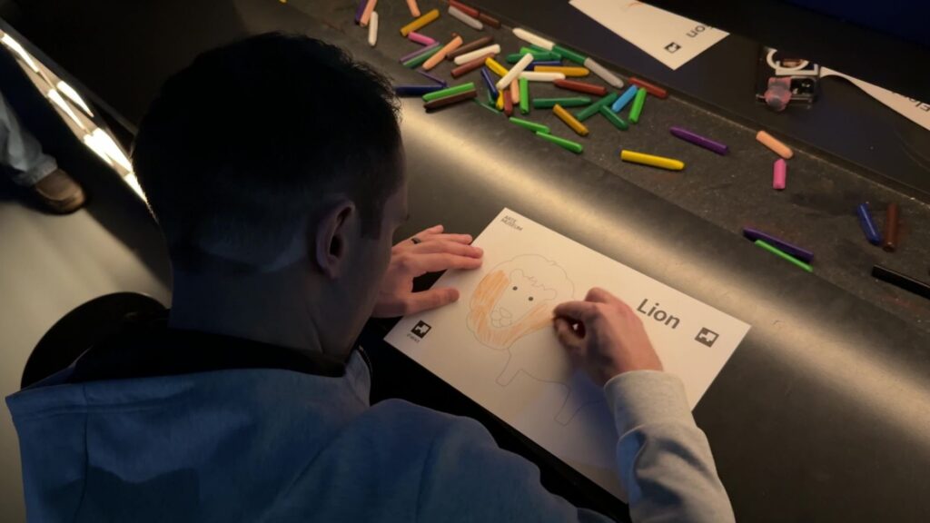 My brother, coloring a picture of a lion to be scanned onto the screen.
