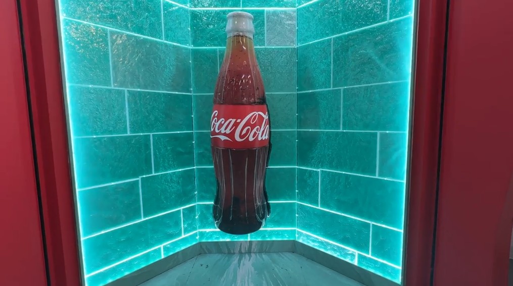A photo opportunity at the Coca Cola store, with an illuminated back wall and a giant glass bottle of Coke in the middle.