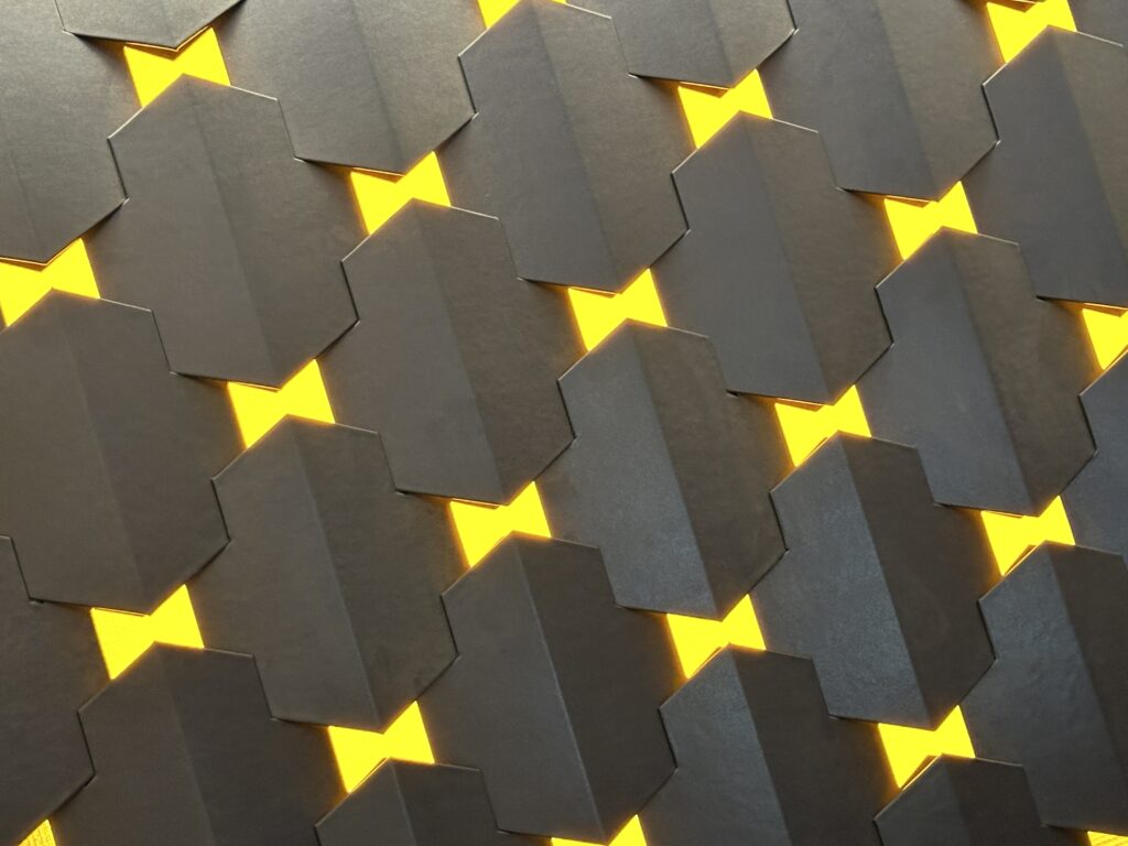 The backdrop wall behind the hotel front desk which is made up of little yellow illuminated bowties separated by black space. 