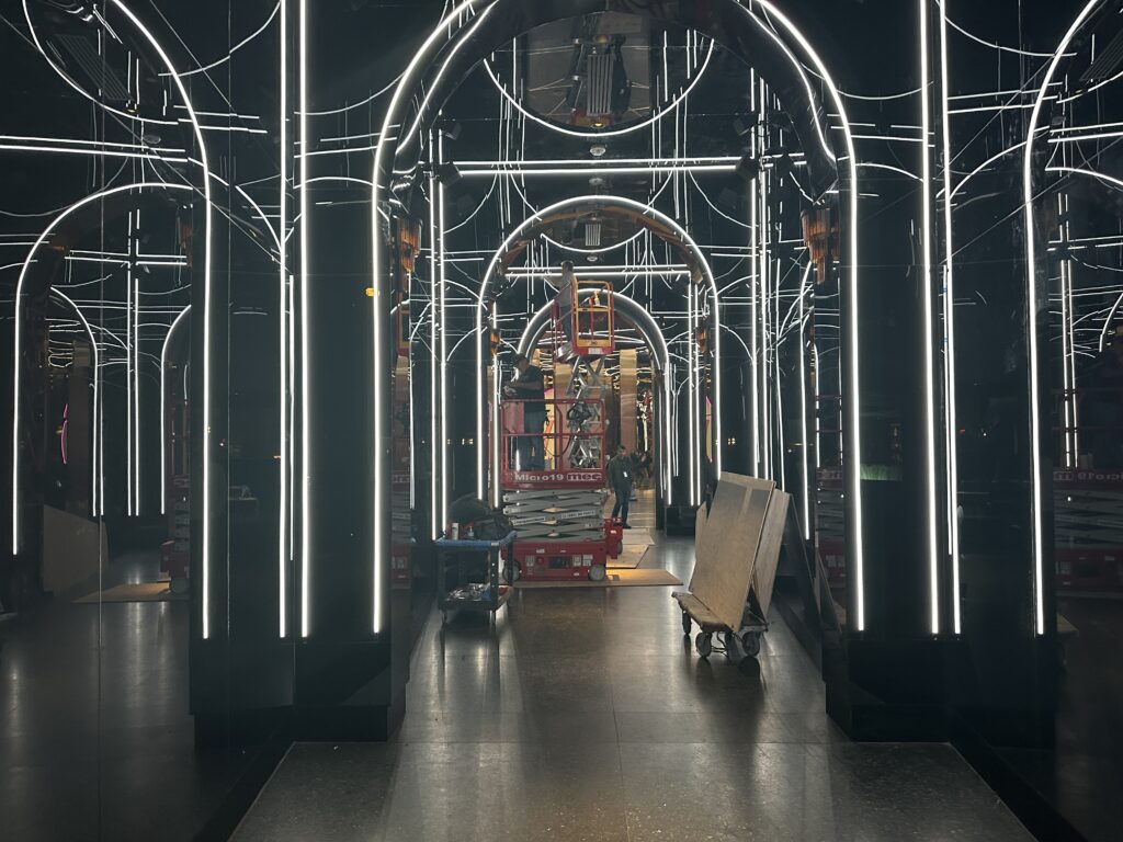 Workers on a lift working in a glass illuminated hallway within the nightclub. 