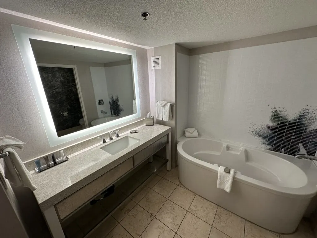 A single sink vanity to the left with a free standing tub to the right. 

