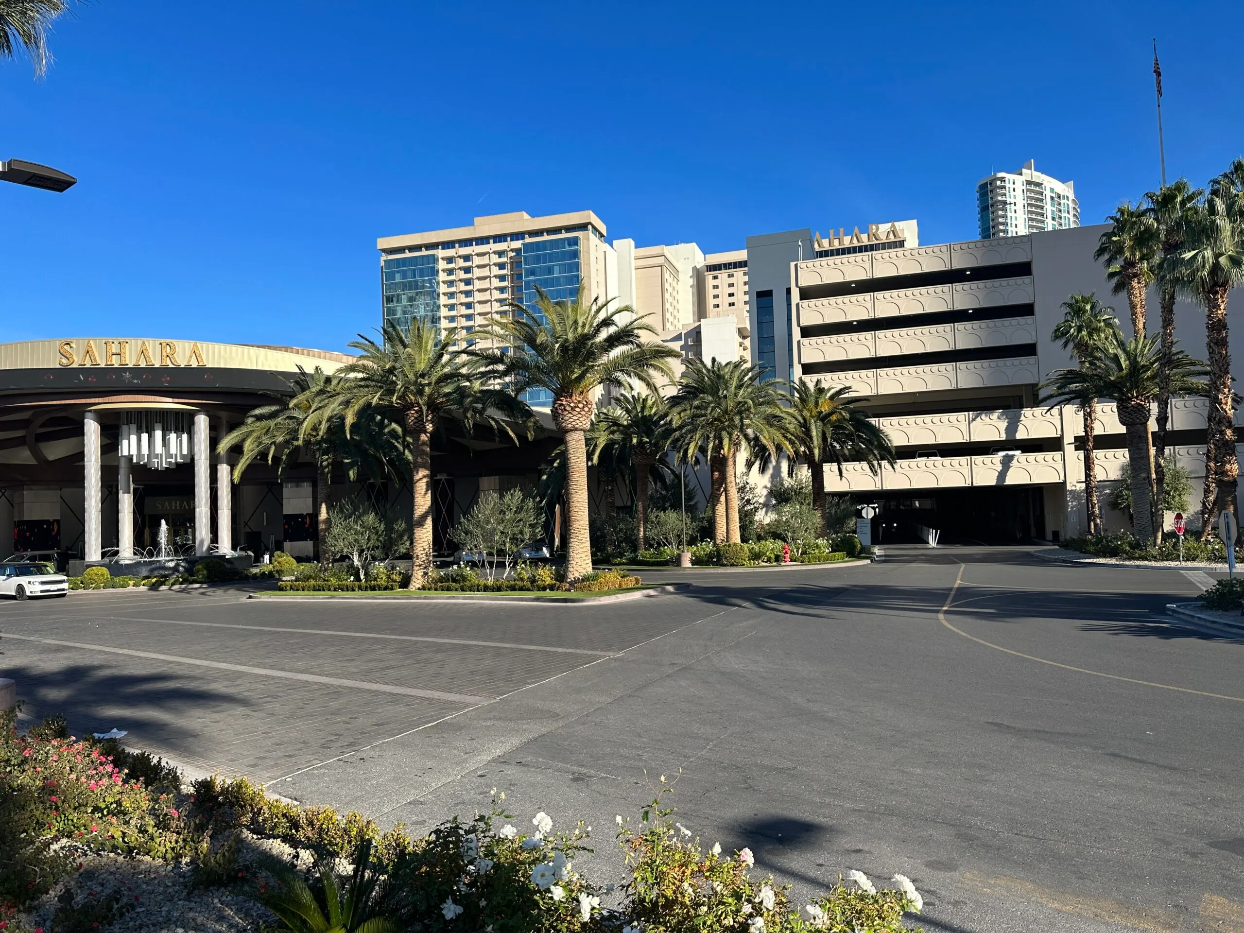 Sahara's porte cochere surrounded by palm trees. The hotel towers are visible in the distance.