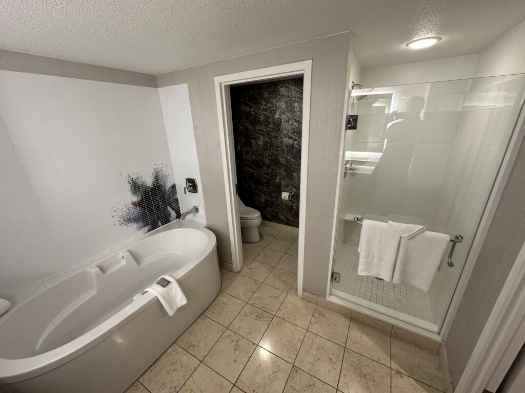 The free standing tub is on the left, a door to the toilet in the middle and a glass enclosed shower to the right. 
