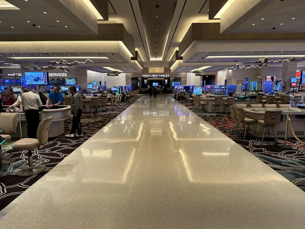 An empty walkway cuts between two banks of table games on either side and leads to the high limit room. 