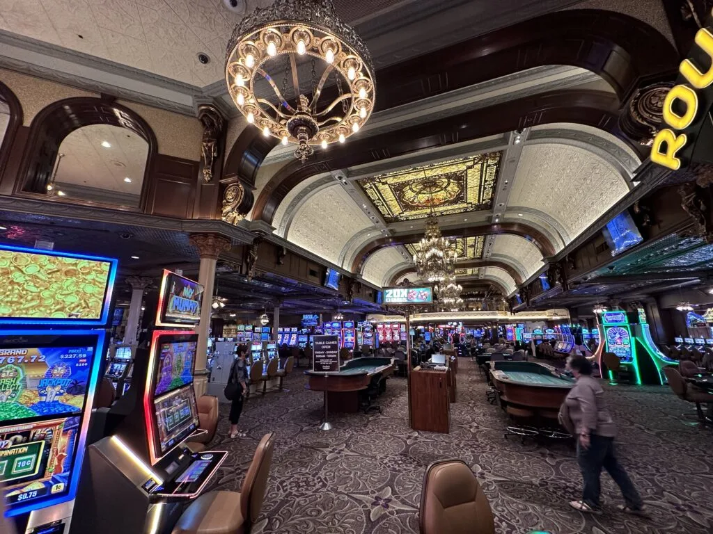 Table game pit at Main Street Station with decorative chandeliers and stained glass on the ceiling above.