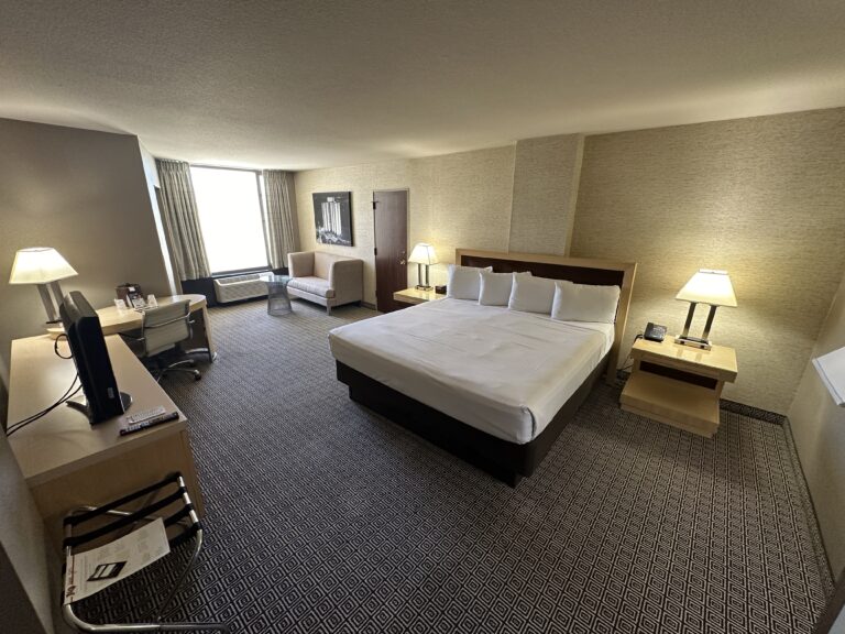 A wide angle shot that shows the king bed, and a window in the background.