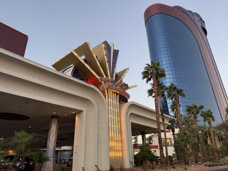 Rio's porte cochere in the foreground with a newon sign that says "Rio" and a hotel tower in the background.