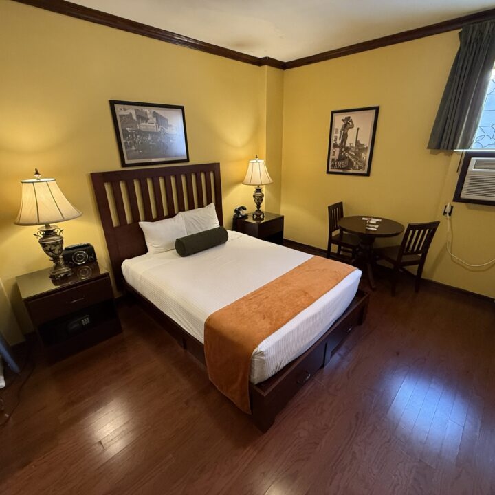 Wide angle shot of my room at Hotel Apache with yellow wall paint and a king bed.