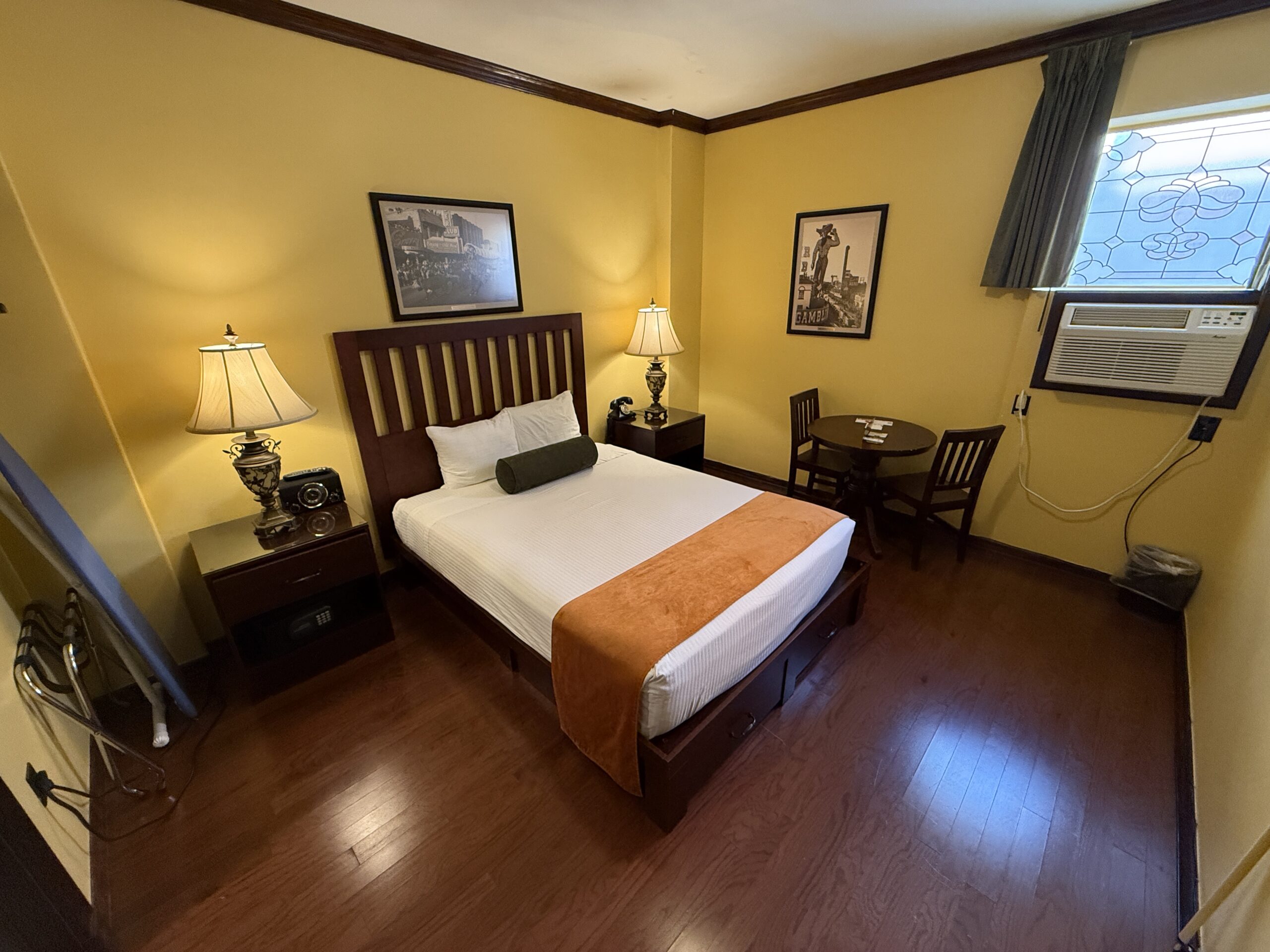 Wide angle shot of my room at Hotel Apache with yellow wall paint and a king bed.