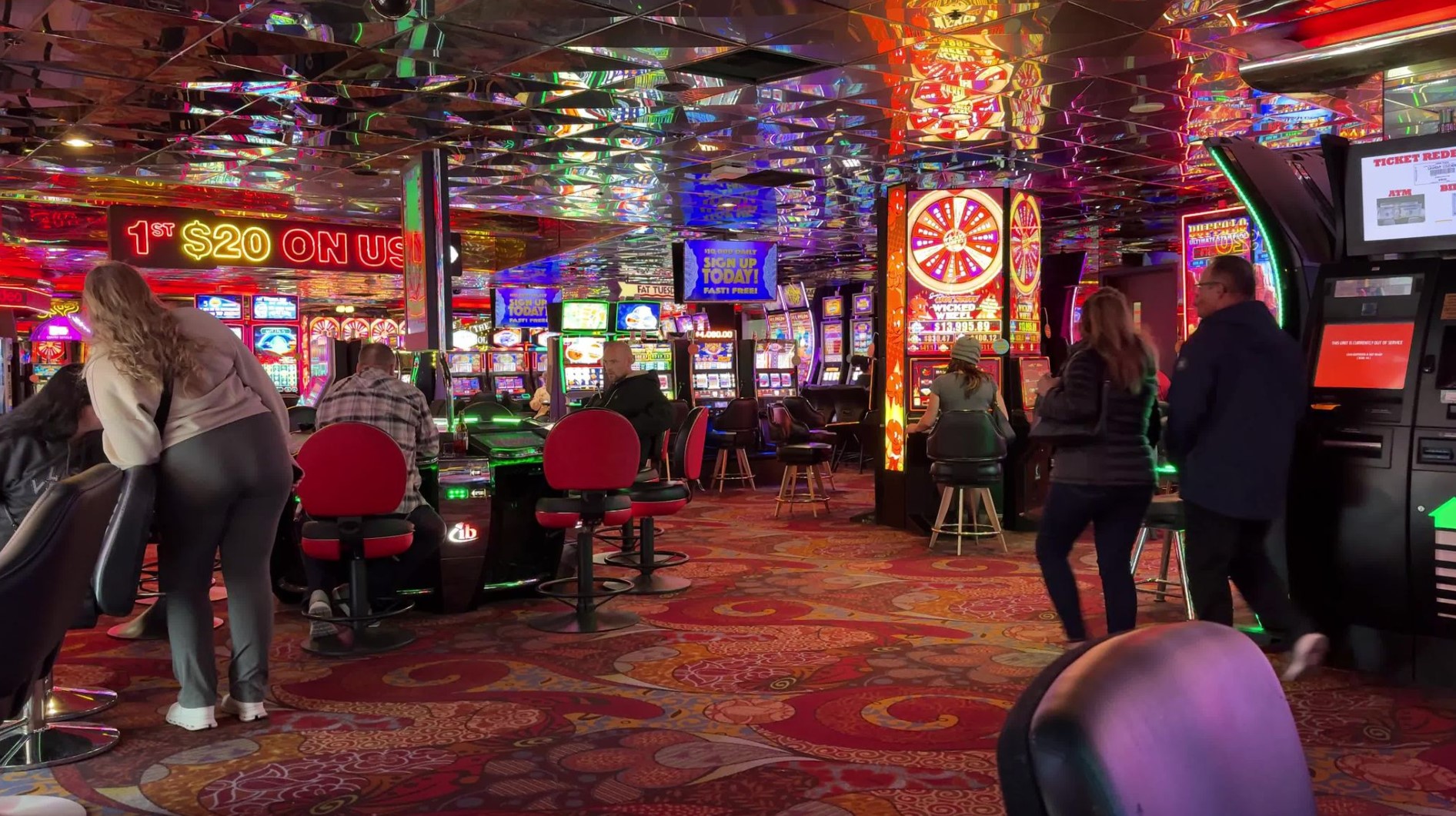 The casino floor, with plenty of slot machines, low reflective ceilings, and and over all dark environment.