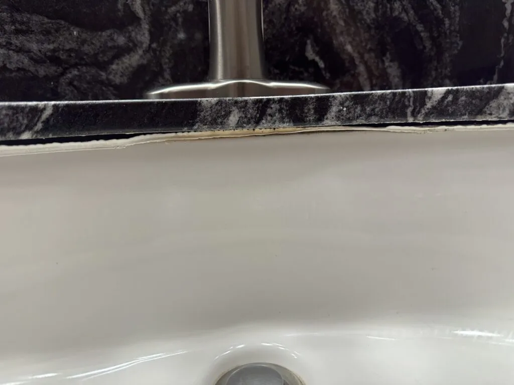 Cracking/decaying caulk line underneath the sink faucet.