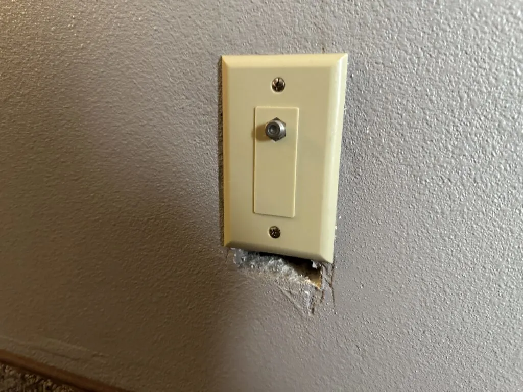 A gaping hole below a coax outlet