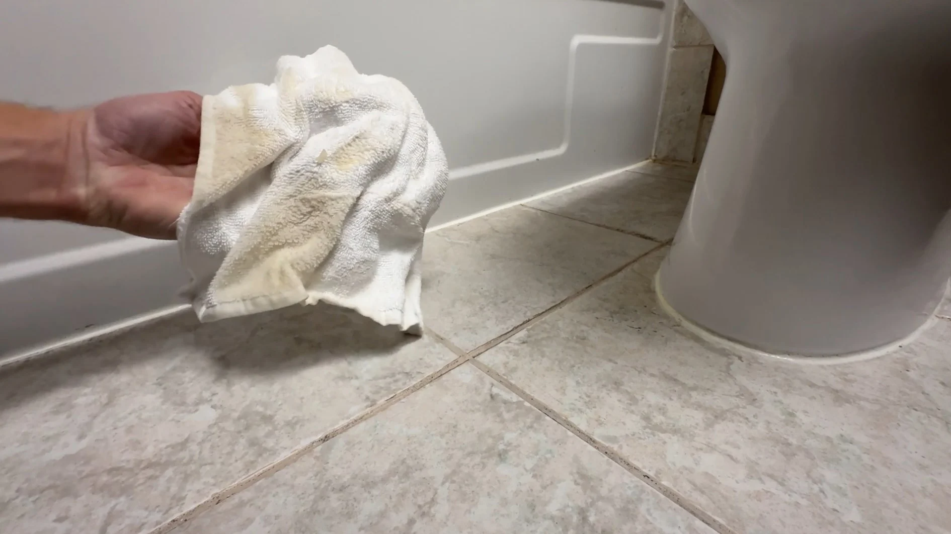 A yellowed, wet rag displayed for the camera after sopping up the puddle.