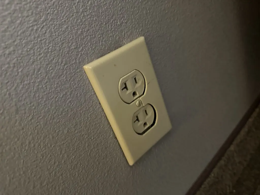 A dated, yellowed, rough looking power outlet.