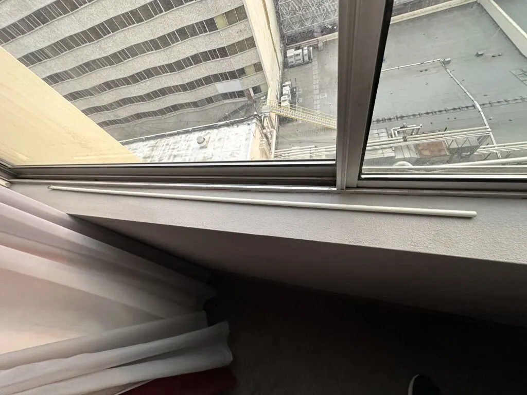A curtain rod laying on the window sill.