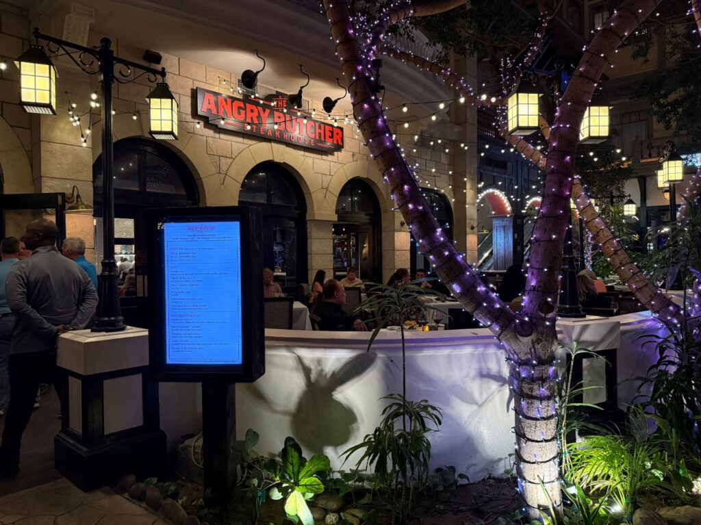 Patio seating at The Angry Butcher overlooking Mystic Falls Park at night. 