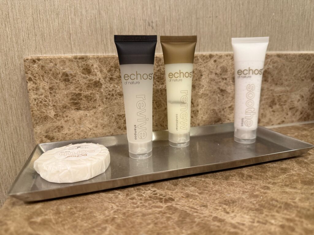 Bath products sit on a silver tray on the counter. 