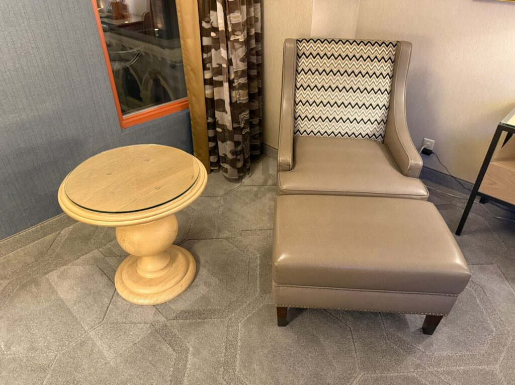 A chair and ottoman next to a small, circular table. 