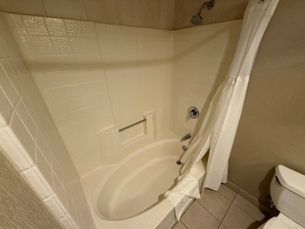 A tub/shower combo with a fake tile surround lining the walls. 