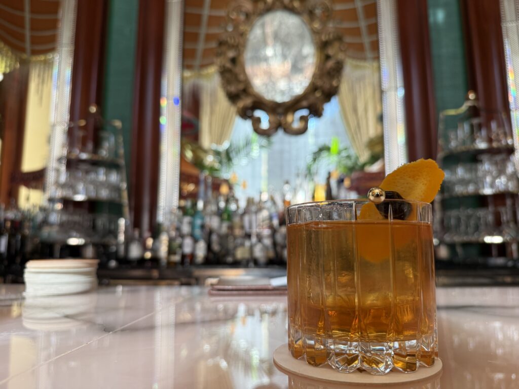 An olde fashioned, sitting in a glass, on the bartop. 