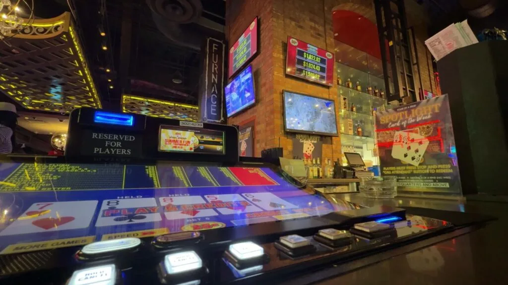 A bartop video poker machine at Furnace Bar, with the progressives posted on a wall in the background.