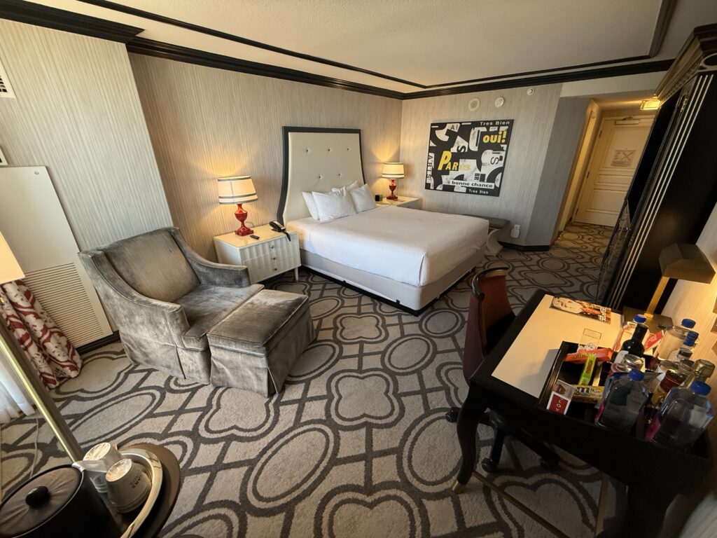 A wide angle of Paris' Bordeaux room, an image with french words hanging above the bed. 