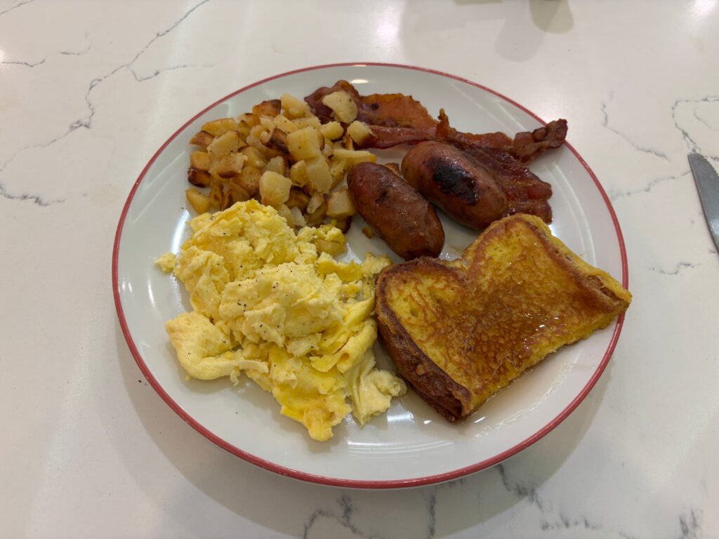 A plate of food from STRAT's buffet that includes eggs, toast, potatoes, and sausage links.