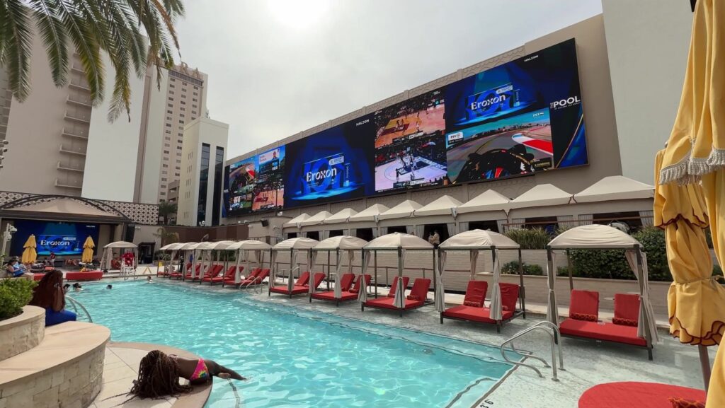 A pool with a giant screen above it displaying multiple sports contests. 