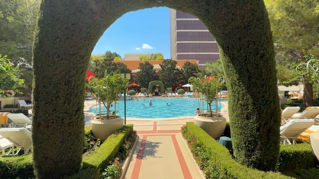 View of Wynn's pool in the background through an arch made of a live plant. 